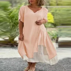 Close-up view of a pink V-neck short sleeve dress with an asymmetrical fake two-piece hem