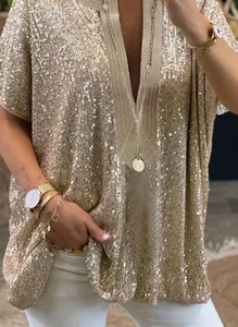 Gros plan sur la texture des paillettes or champagne d'une chemise ample à col en V