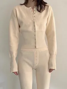 Vista de cerca de un conjunto de punto acanalado crema con una elegante chaqueta de botones