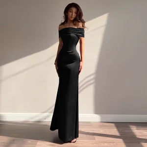 Elegant off-the-shoulder black mermaid evening dress worn by a model in sunlight