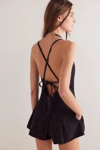 Back detail view of a black denim romper featuring cross straps and a tie-back design.