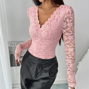 Détail d'un body rose en dentelle à manches longues avec un décolleté plongeant en V.