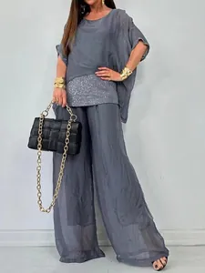 Detail des grauen Chiffon-Zweiteilers mit Pailletten-Patchwork und weiter Hose.