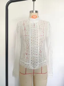 Detailed view of white lace blouse with standing collar and frog fasteners on mannequin