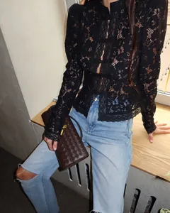 Detail shot of a black lace crochet long-sleeve shirt with mandarin collar buttons.
