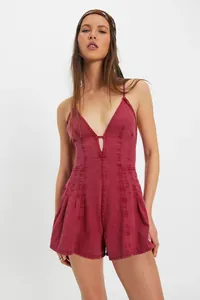 Full-length view of a burgundy denim sleeveless romper with pleated shorts on a model