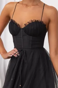 Close-up detail of a black mesh evening dress featuring a corset bodice and ruffles.