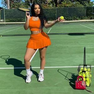 Modèle portant un ensemble de tennis orange à deux pièces sur un court de tennis