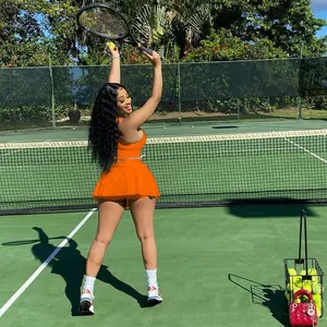Vue complète de l'ensemble de sport orange porté par un mannequin sur un court de tennis
