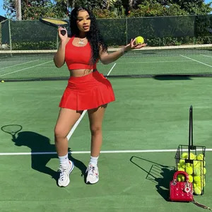 Vue détaillée d'un ensemble haut court et jupe plissée de sport rouge sur un court de tennis.
