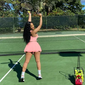 Femme portant un ensemble de sport rose avec débardeur et jupe sur un court de tennis