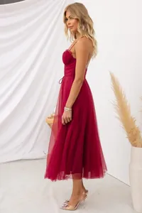 Side profile of an elegant burgundy tulle evening dress with delicate spaghetti straps.