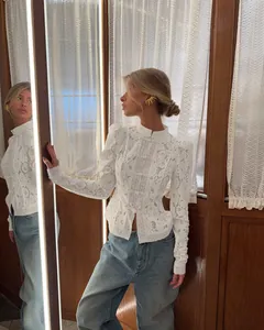 Detailed shot of a white lace crochet blouse with stand collar and button details