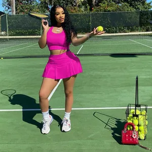Femme élégante portant un ensemble de tennis rose vif sur un court de tennis vert en extérieur