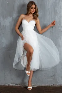 Detailed view of a white spaghetti strap tulle evening dress featuring a sexy high slit