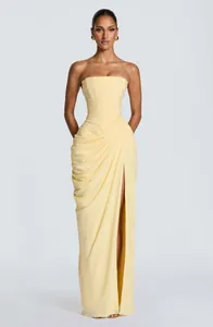 Detailed view of yellow strapless maxi dress featuring asymmetrical pleats and slit