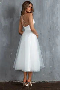 Elegant detail of a white tulle evening dress with cross straps and backless design.