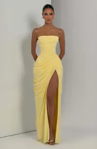 Detalle que muestra el drapeado asimétrico y la abertura alta de este vestido amarillo