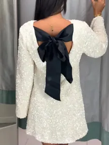 Detail of white sequined dress featuring a large black satin bow on the back.