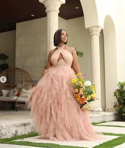 Elegant pink tiered tulle evening gown with halter neckline in a lush patio setting