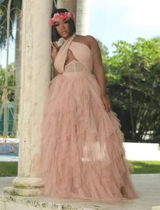 Elegant blush pink tiered tulle prom dress with halter neck and corset bodice detail.
