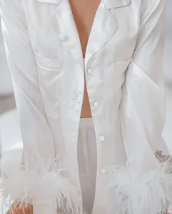 Gros plan d'un haut de pyjama en satin blanc luxueux avec des poignets en plumes élégants