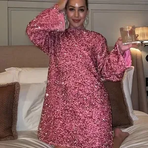 Detail of pink sequin long sleeve mini dress with a loose fit and round neckline.