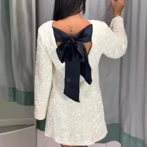 Elegant white sequin long sleeve mini dress featuring a large black bow on an open back