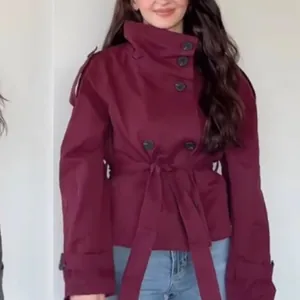 Macro view of a burgundy retro double-breasted short trench coat with a waist tie detail.