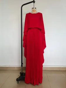 Detailed view of red pleated batwing sleeve top and long skirt set on mannequin
