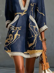 Detail of navy blue resort dress with gold abstract print and delicate lace trim