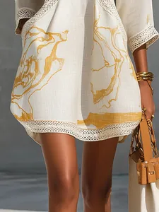 Close-up of cotton linen dress featuring gold abstract print and delicate lace trim.
