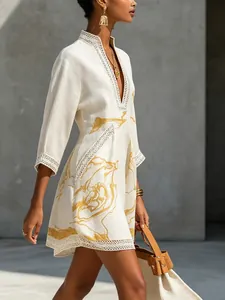 Close-up detail of cotton-linen mini dress featuring V-neck lace trim and gold abstract print