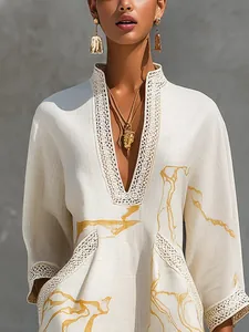Detail of white linen dress with gold abstract print and delicate lace-trimmed V-neckline.