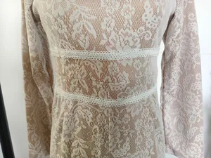 Detailopname van elegant bloemenkant en de geborduurde taille van de slim jumpsuit.