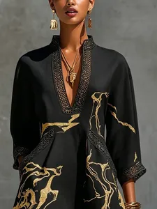 Detailed view of the gold abstract print and black lace trim on a V-neck dress