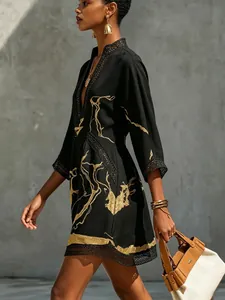 Side view of black V-neck mini dress with gold abstract print and delicate lace trim