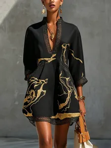 Close-up of black V-neck vacation dress with gold abstract print and lace trim details