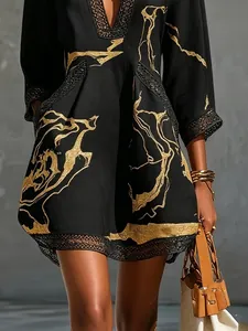 Detail view of black resort mini dress featuring gold abstract print and delicate lace trim.