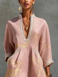 Detail of pink resort dress featuring golden abstract print and lace-trimmed V-neckline