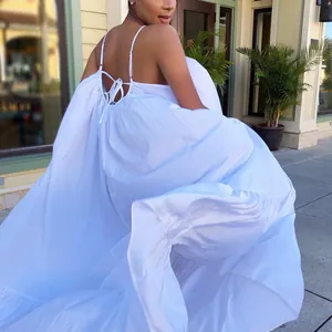 Elegant white backless maxi dress with spaghetti straps and voluminous tiered skirt
