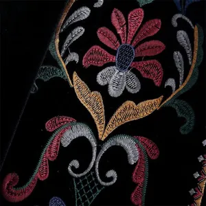 Gros plan des broderies florales complexes sur un tissu en velours noir haut de gamme.