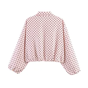Vista trasera detallada de una chaqueta rosa con mangas abullonadas, lunares negros y cuello.