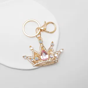 Close-up of a sparkling gold crown keychain with pink pear-shaped crystal