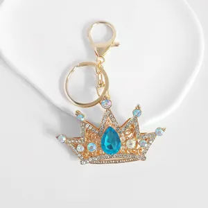 Detailed view of a gold-tone crown keychain with sparkling blue and white rhinestones
