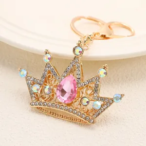 Close-up of a sparkling gold crown keychain with pink teardrop crystal and rhinestones.