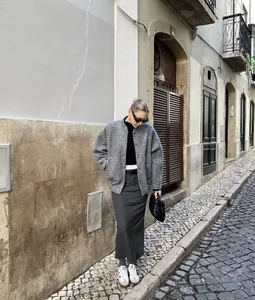 Woman wearing grey textured jacket and pinstripe skirt on a European cobblestone street