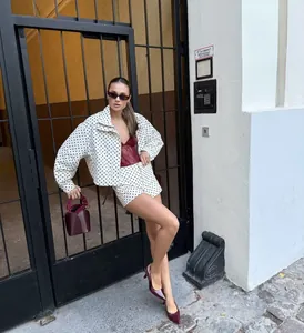 Fashionable woman wearing a white polka dot seersucker jacket set posing outdoors