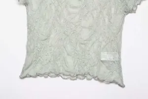 Close-up of light green vintage lace T-shirt showing flocking texture and ruffled hem