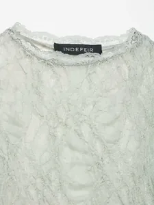 Close-up detail of vintage light green flocked lace fabric and neckline texture.